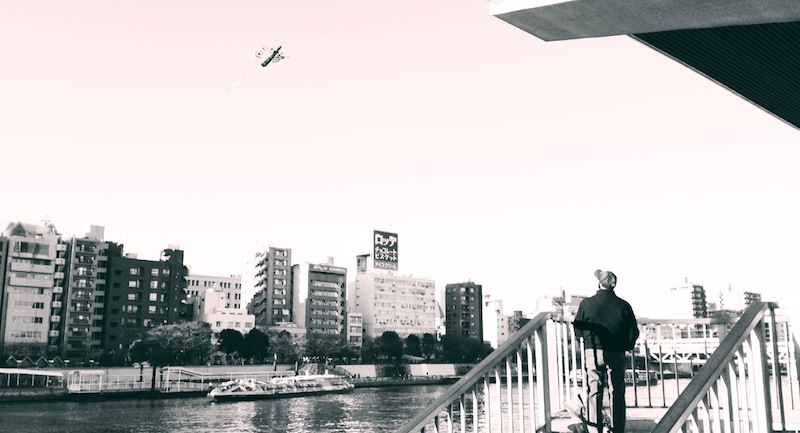 Hombre volando la cometa en el río